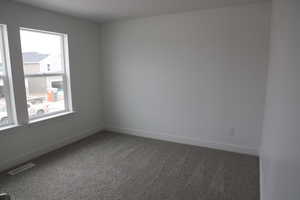 Unfurnished room featuring carpet flooring, baseboards, and visible vents