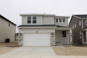 View of front of house with stone siding, an attached garage, driveway, and roof with shingles
