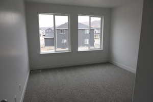 Carpeted spare room with a residential view, baseboards, and visible vents