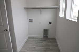 Washroom featuring baseboards, washer hookup, laundry area, wood finished floors, and hookup for an electric dryer