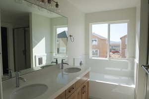 Full bath with double vanity, a bath, and a sink
