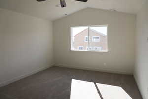 Empty room with visible vents, lofted ceiling, ceiling fan, and carpet flooring
