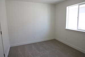 Empty room featuring carpet flooring and baseboards