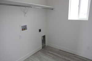 Clothes washing area featuring washer hookup, wood finished floors, baseboards, hookup for an electric dryer, and laundry area