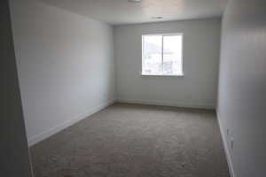 Carpeted empty room with visible vents and baseboards