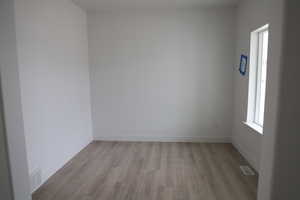 Unfurnished room with light wood-style flooring, baseboards, and visible vents