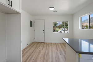 Unfurnished dining area with visible vents, electric panel, baseboards, and light wood-type flooring