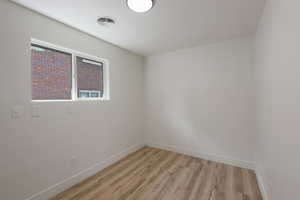 Spare room with visible vents, baseboards, and light wood-style flooring