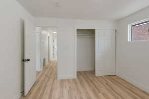 Unfurnished bedroom with visible vents, light wood-style floors, baseboards, and a closet