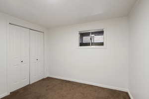 Unfurnished bedroom with baseboards, a closet, dark carpet, and ornamental molding