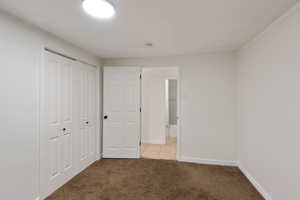 Unfurnished bedroom featuring light carpet, baseboards, and a closet