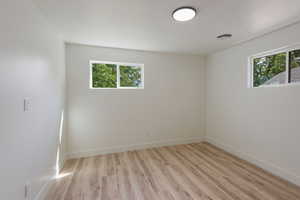 Unfurnished room with light wood-type flooring, visible vents, baseboards, and a healthy amount of sunlight