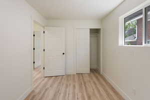 Unfurnished bedroom with light wood finished floors, a closet, and baseboards