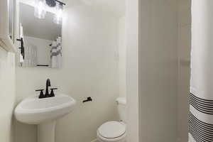 Bathroom with curtained shower, toilet, and a sink