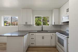 Kitchen with decorative backsplash, white appliances, a peninsula, and a sink