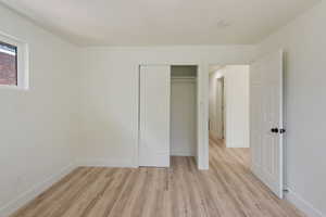 Unfurnished bedroom with light wood-style flooring, baseboards, and a closet