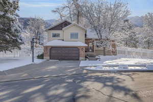 View of front of house with brick siding, a mountain view, fence, and a garage