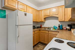 Kitchen with light brown cabinets, white appliances, light countertops, and a sink