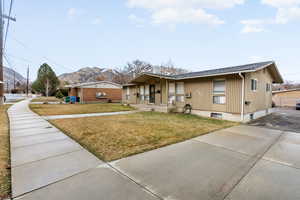 View of front of home featuring a mountain view, concrete driveway, and a front yard