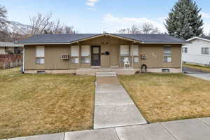 View of front of property featuring a front lawn, fence, covered porch, and roof with shingles