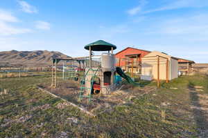 Community playground with a mountain view, a trampoline, and fence
