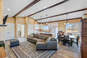 Living area featuring vaulted ceiling with beams, recessed lighting, light wood-type flooring, and baseboards