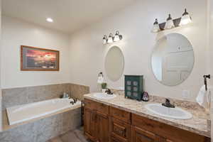 Full bath with a bath, double vanity, and a sink