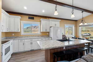 Kitchen with a sink, a kitchen breakfast bar, white appliances, and light countertops