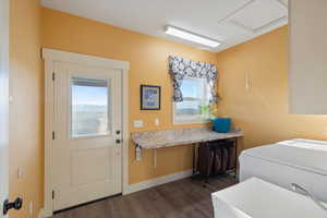 Clothes washing area with dark wood-type flooring, a sink, baseboards, washer / dryer, and laundry area