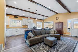 Living room with visible vents, baseboards, lofted ceiling with beams, recessed lighting, and light wood-style floors