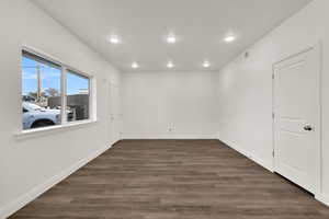 Empty room with dark wood-style floors and recessed lighting