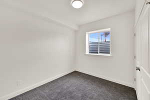 Empty room with baseboards and dark colored carpet