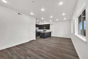 Kitchen featuring open floor plan, light countertops, a peninsula, dark wood-type flooring, and appliances with stainless steel finishes