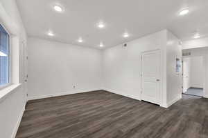 Unfurnished room with dark wood-style flooring, recessed lighting, and electric panel