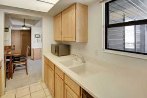 Kitchen featuring a sink, light brown cabinets, black microwave, and light countertops