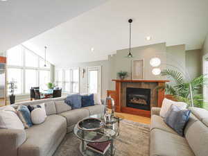 Living room featuring a glass covered fireplace, recessed lighting, wood finished floors, and vaulted ceiling