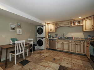 Kitchen with a sink, recessed lighting, appliances with stainless steel finishes, and stacked washer and dryer
