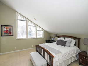 Bedroom 1, light colored carpet, and vaulted ceiling and architectural designer cement wall