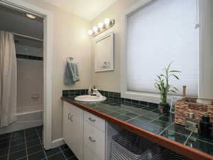 Full bathroom with tile patterned floors, vanity, and shower / bathtub combination with curtain