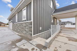 View of home's exterior with fence, board and batten siding, stone siding, and roof with shingles