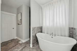 Full bath with wainscoting, tile walls, and a freestanding tub