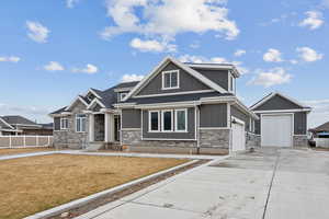 Craftsman-style home with stone siding, concrete driveway, a front lawn, and fence