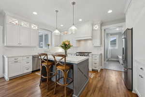 Kitchen featuring stainless steel appliances, white cabinetry, a kitchen island, and light countertops