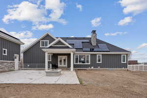 Back of property with solar panels, a patio area, french doors, and board and batten siding