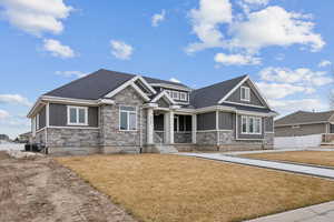 Craftsman house with board and batten siding, fence, a front yard, a sunroom, and stone siding