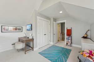 Recreation room with light colored carpet, baseboards, and lofted ceiling