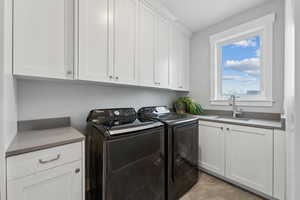 Laundry room featuring a sink, cabinet space, and separate washer and dryer