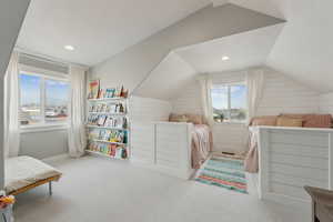 Bedroom featuring wood walls, carpet, and lofted ceiling
