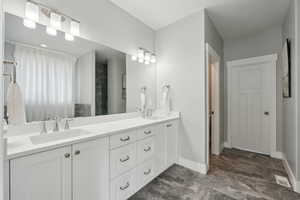 Bathroom with double vanity, baseboards, visible vents, and a sink