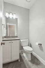 Half bath with vanity, toilet, and baseboards